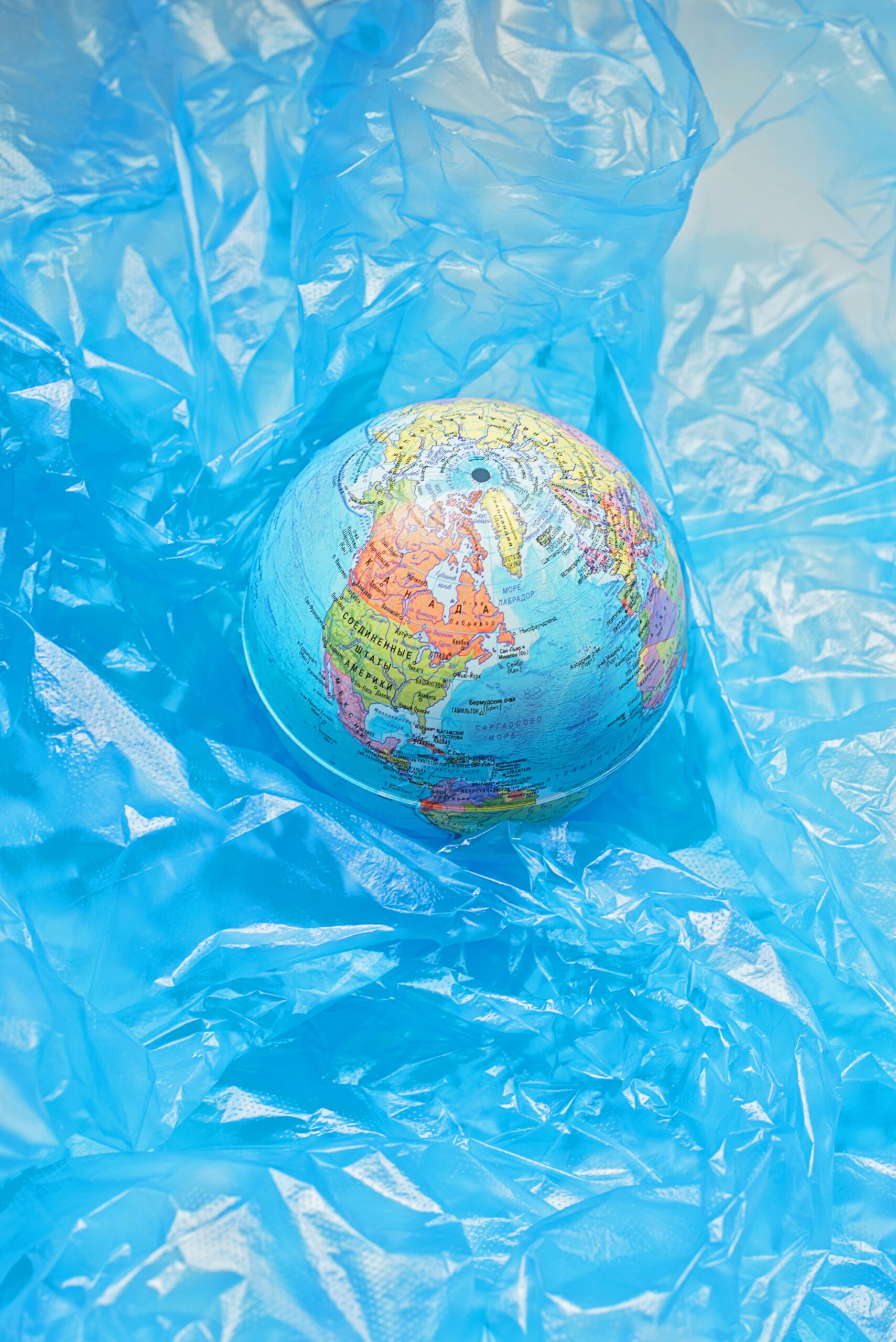 A globe surrounded by blue plastic highlighting global pollution.