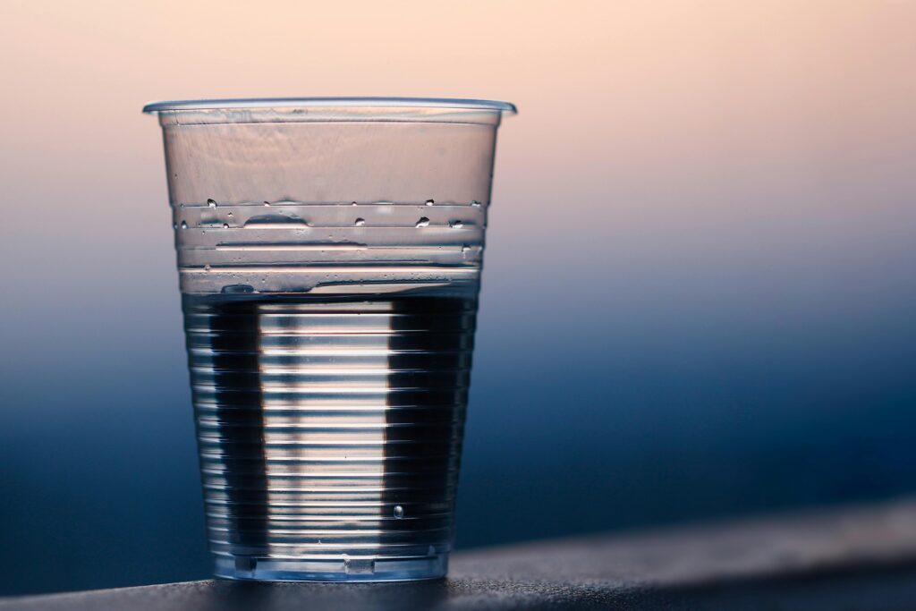 Close-up of a plastic cup filled with water against a soft dusk background.